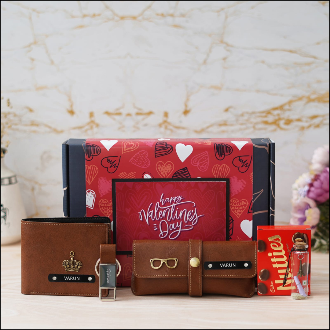 Personalized Giftings for Valentine days for him consisting of leather wallet, keychain, and sunglasses case with the name , alongside a box of chocolates and a Valentine's Day card.